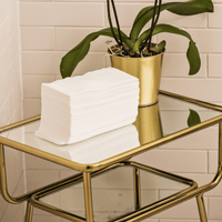 Image of a stack of Scrummi View details for Luxury Hand Towels Luxury Hand Towels in white, neatly arranged in a salon. The towels, with their textured waffle weave, are displayed to highlight their soft, absorbent material. The disposable and biodegrada