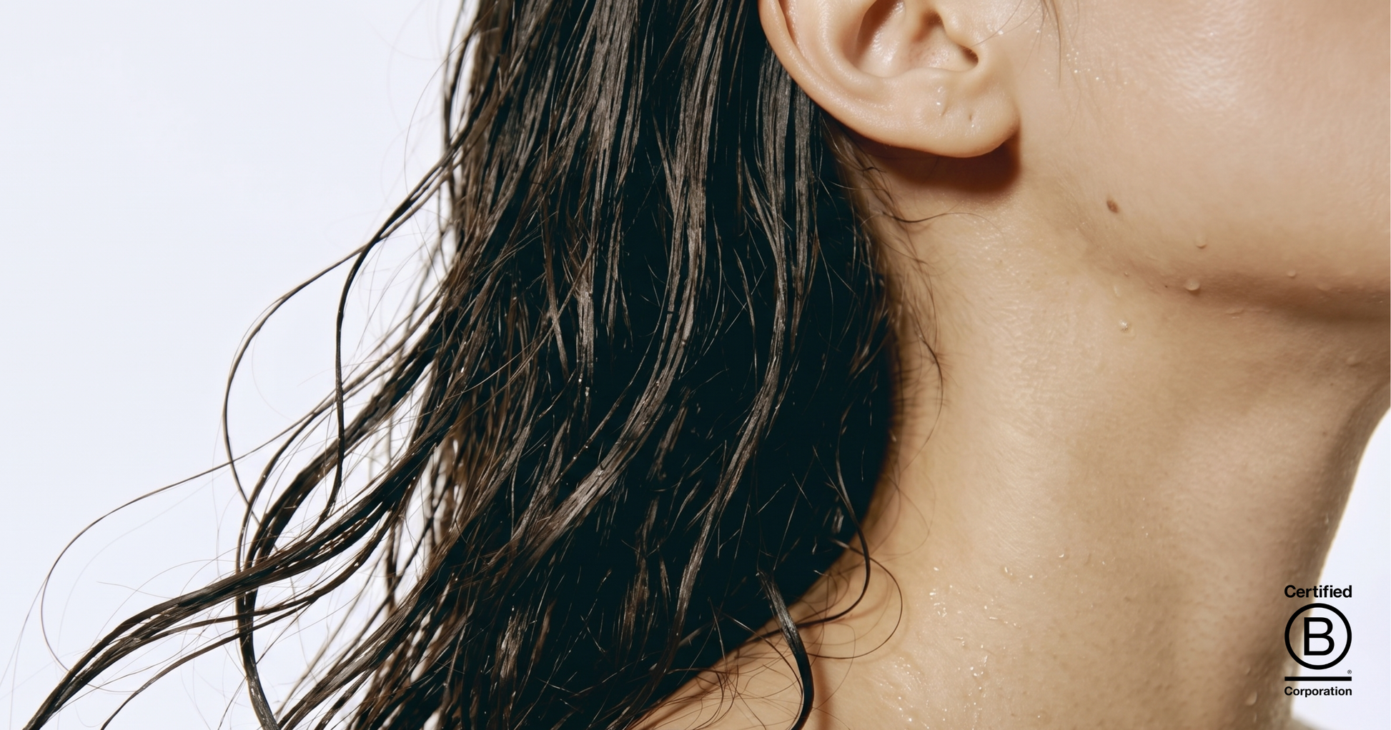 Close-up of a person's neck and shoulder with wet hair against a light background